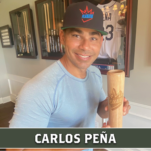 Carlos Peña smiling and holding a wooden Dugout Mugs baseball bat mug with the Plakata logo.